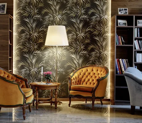 zwei gelbe Louis Seize-Sessel und Stehlampe vor Blättertapete im Hotel Reppert