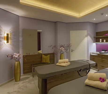 Paarbehandlungsraum im Hotel Reppert mit zwei grauen Liegen und zwei goldenen großen Vasen