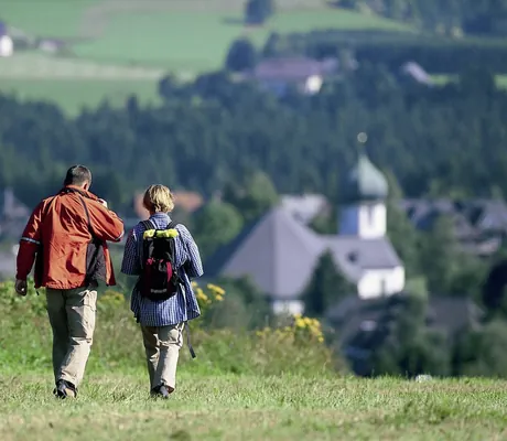 Paar wandert in Hinterzarten auf Kirchturm zu nahe Hotel Reppert