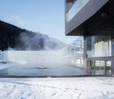 Frau schwimmt im Outdoorpool der Riederalm im tiefen Schnee