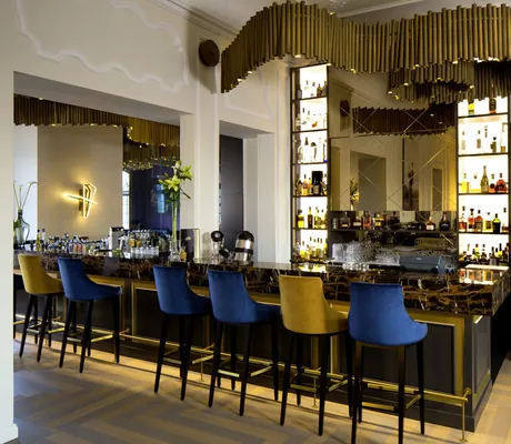 Bar im Schloss Fleesensee mit Röhrenlampe an der Decke und blauen und gelben Barhockern