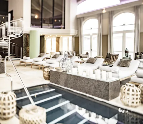 Ruhebereich im Schloss Fleesensee mit Treppenabgang zum Pool und beigen Polsterliegen