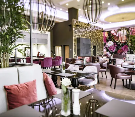 Restaurant Orangerie im Schloss Fleesensee mit altrosafarbenen Stühlen und Polstern und Rosentapete