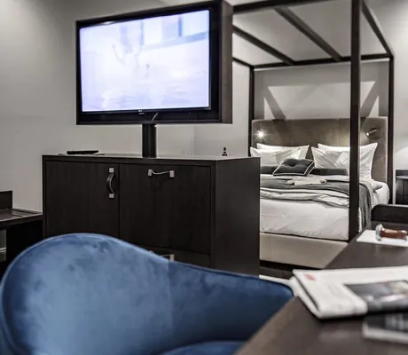 Zimmer im Schloss Fleesensee mit modernem Himmelbett und baluem Stuhl am Schreibtisch