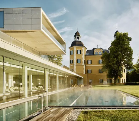 Outdoorpool vor dem Ruhebereich des Schlosshotel Velden mit Blick auf das Schloss