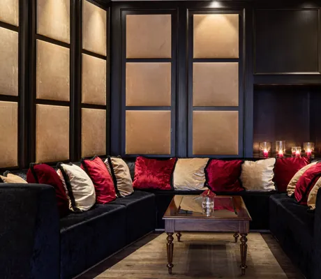 gemütliche Kuschelecke mit roten und weißen Kissen und braun-schwarzer Vertäfelung im Schlosshotel Velden