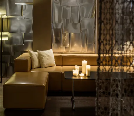 gelbe Ledersofaecke hinter einem Vorhang mit Kerzen auf dem Tisch im Schlosshotel Velden