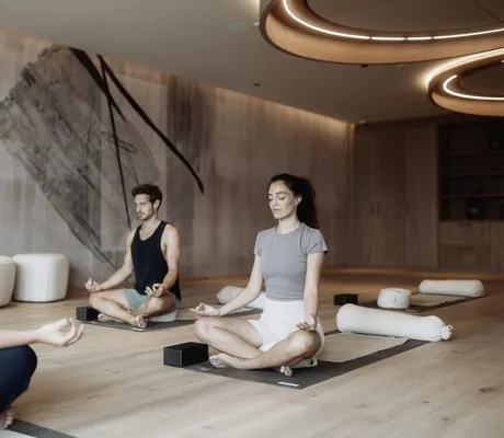 Paar macht Yoga im Yogaraum mit runden Deckenleuchten im Hotel Solvie