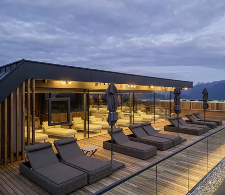 Sky Terrasse mit grauen Ruheliegen im Sonnenberg Panorama Dolomites Wellbeing in der Abenddämmerung