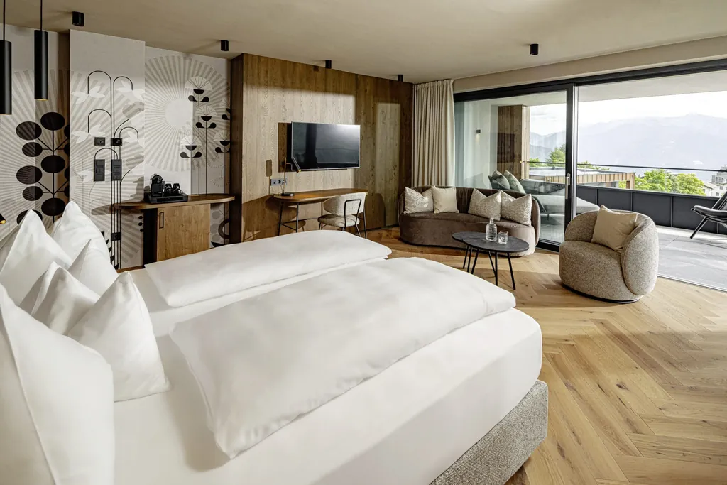 Zimmer im Sonnenberg Panorama Dolomites Wellbeing mit Designelementen an der Wand und grauem Sessel
