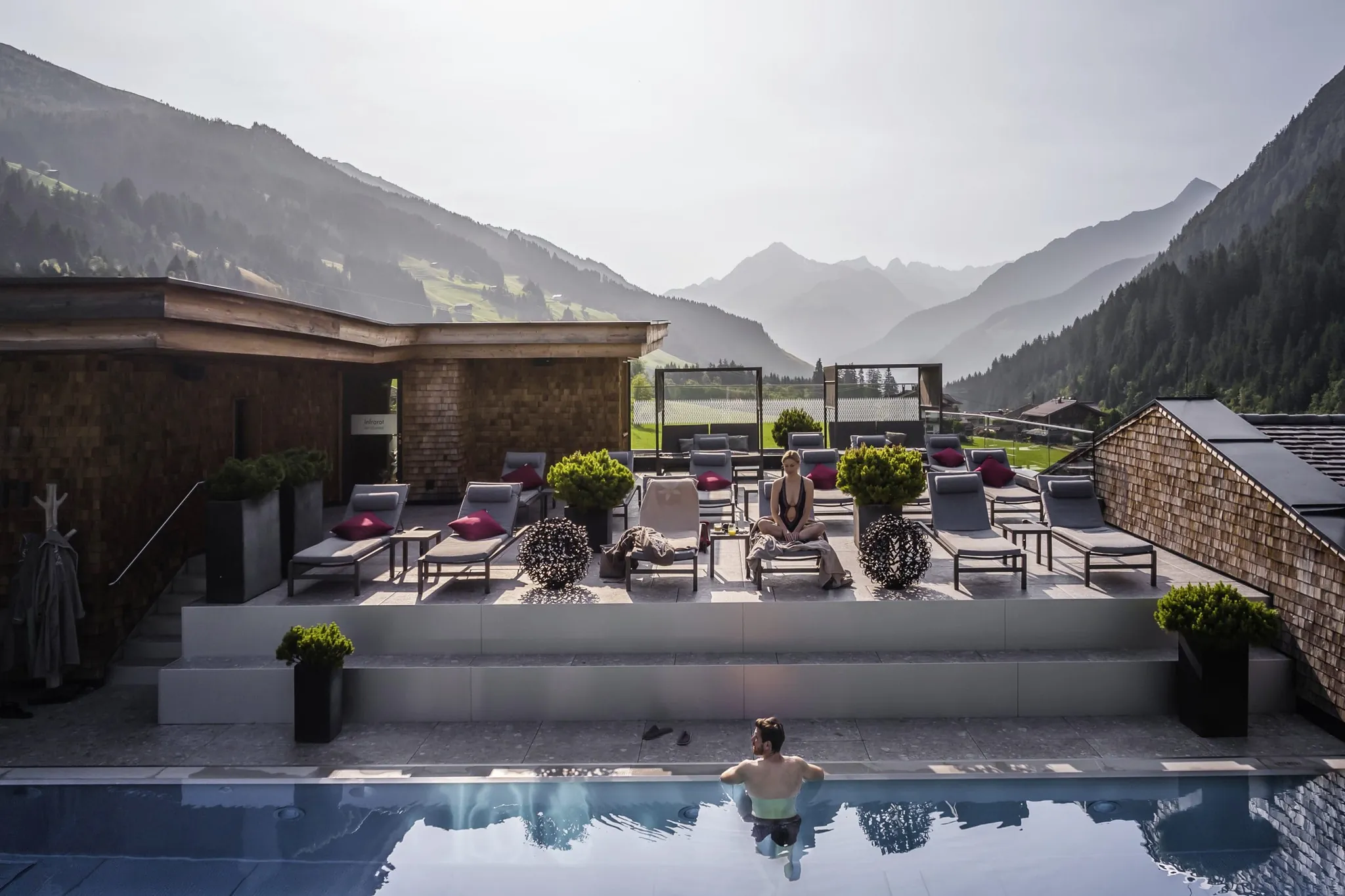 Mann steht am Beckenrand des Skypools im Tuxerhof und Frau sitzt auf einer Liege am Rand