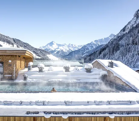 Mann liegt im Skypool des Tuxerhof im tiefen Winter bei strahlendem Sonnenschein