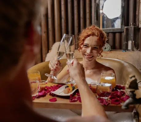 rothaarige Frau stößt in Kupferwanne im Vier Jahreszeiten am Schluchsee mit Mann mit Sekt an