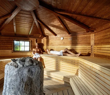Paar liegt in runder Sauna des Vier Jahreszeiten am Schluchsee mit Steinofen in der Mitte