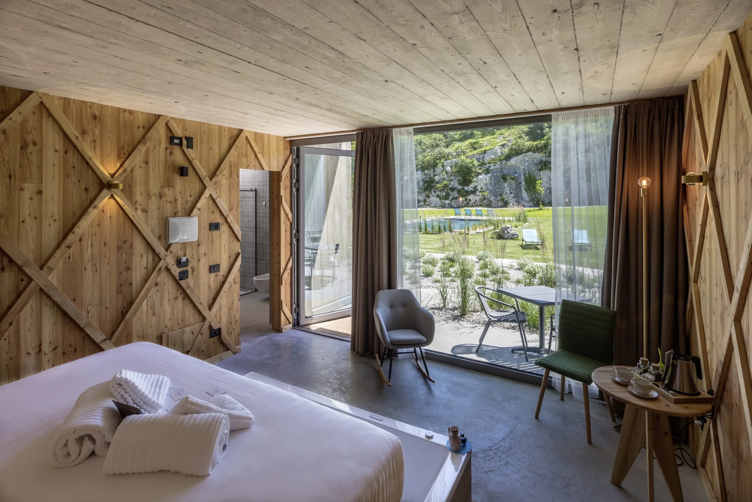 Suite aus Holz mit gro&szlig;em Fenster und Blick auf Garten und Outdoor-Biopool im Agritur La Dolce Mela