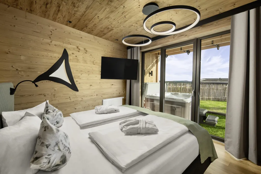 Schlafzimmer im Hunderesort Waldeck mit runden Deckenleuchten und Blick auf den Outdoor-Whirlpool
