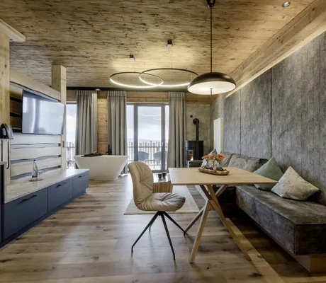 Blick in den Wohnbereich des Lofts im Hunderesort Waldeck mit freistehender Badewanne und langer Polsterbank