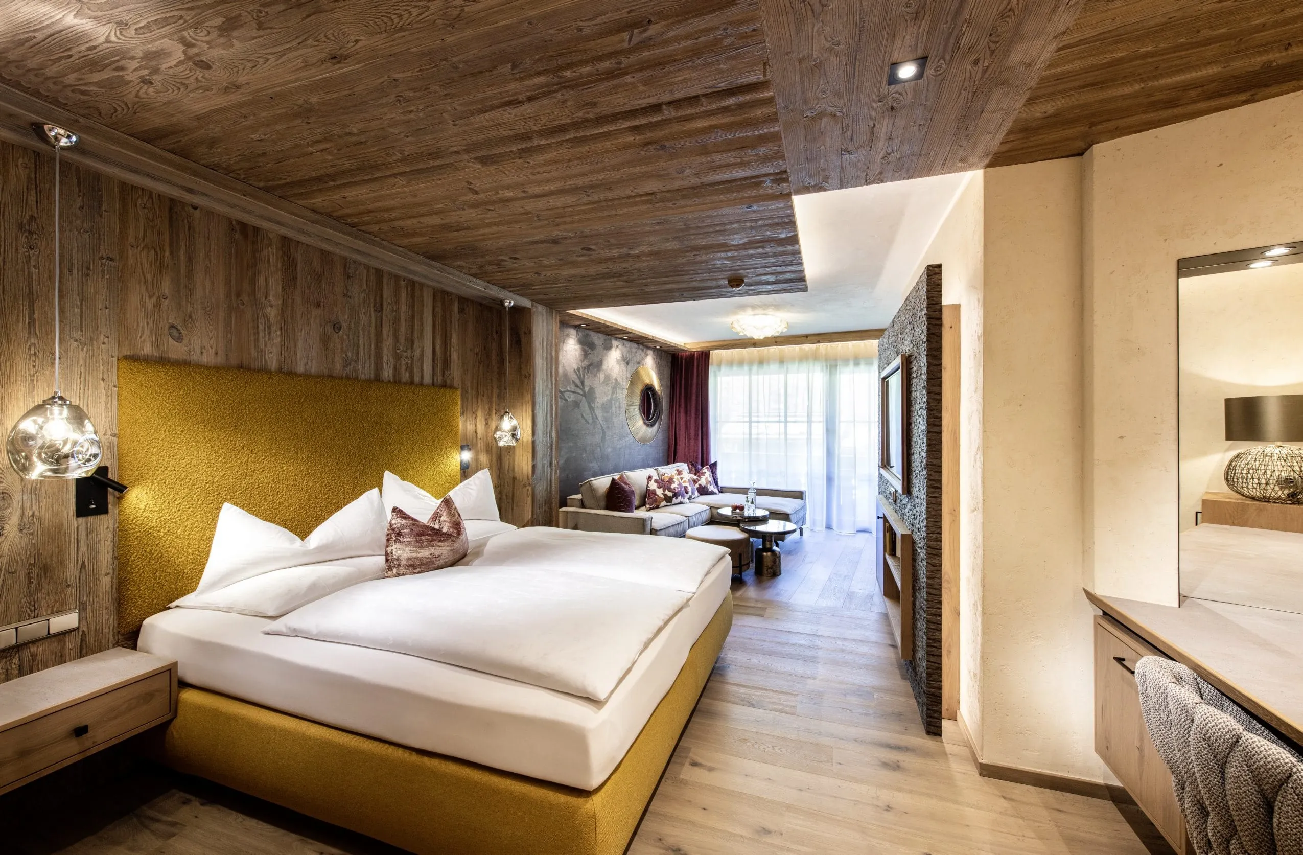 gro&szlig;e Familysuite im Alpin SPA Hotel Tuxerhof mit gelbem Bett und grauer Sofaecke