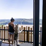 Frau steht mit Hund am Balkon des Lofts im Hunderesort Waldeck und schaut in die Ferne
