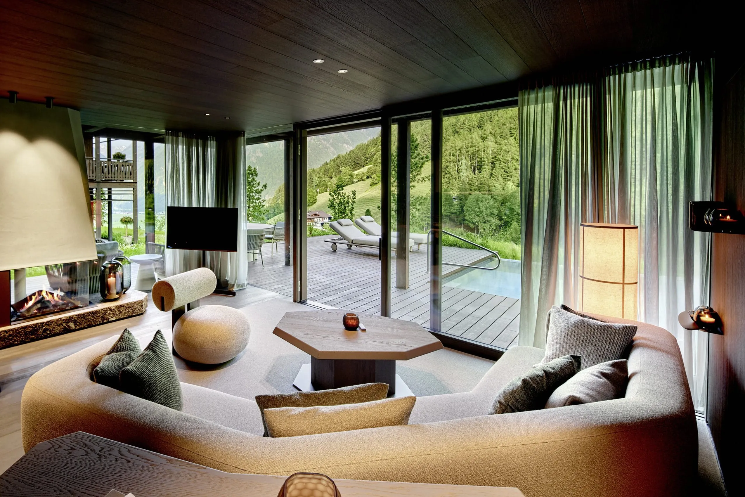 große Sitzlounge im Wohnzimmer der Amonti Chalets mit Kamin und Blick auf den privaten Pool