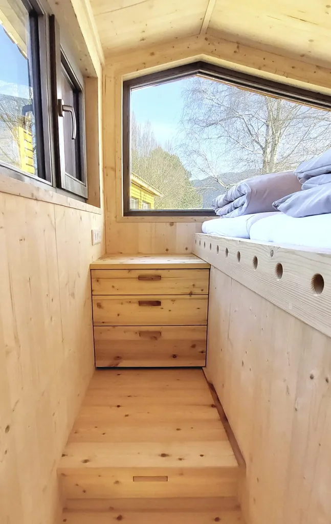 Schlafbereich mit smartem Stauraum und großen Fenstern im Tiny House des SEINZ Wisdom Resort
