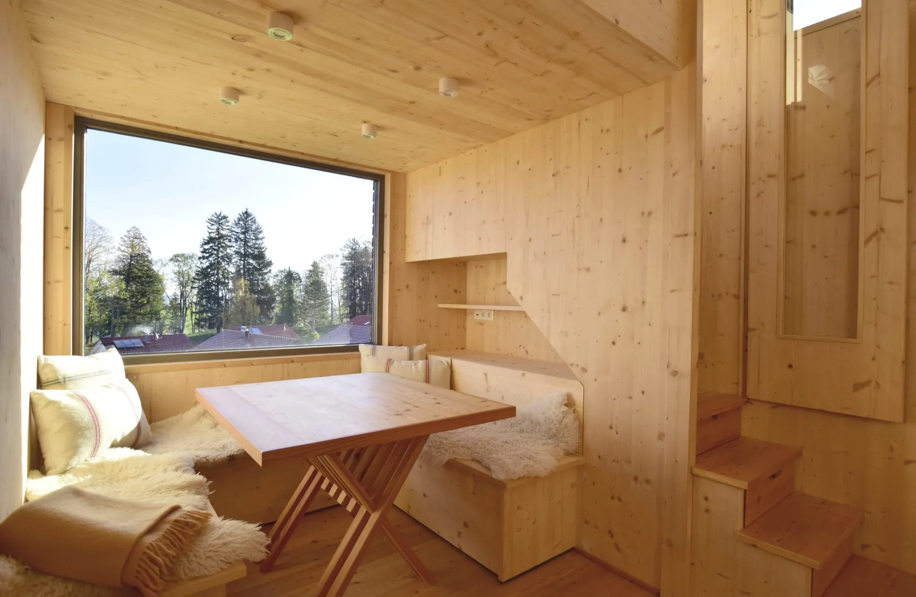 Komplett aus Holz erbautes Tiny House mit Essecke und großem Fenster