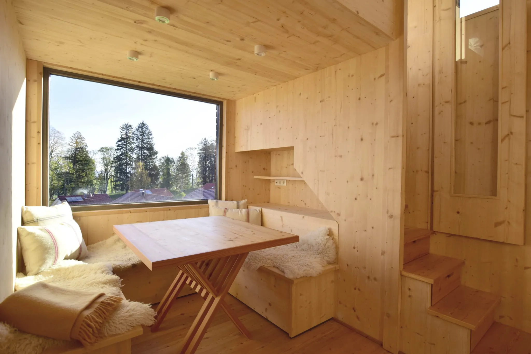 Komplett aus Holz erbautes Tiny House mit Essecke und großem Fenster