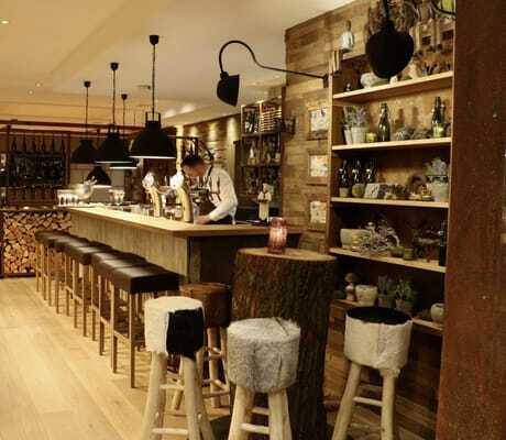 Bar in Wellings Parkhotel mit braunen Barhockern und Holzscheiten