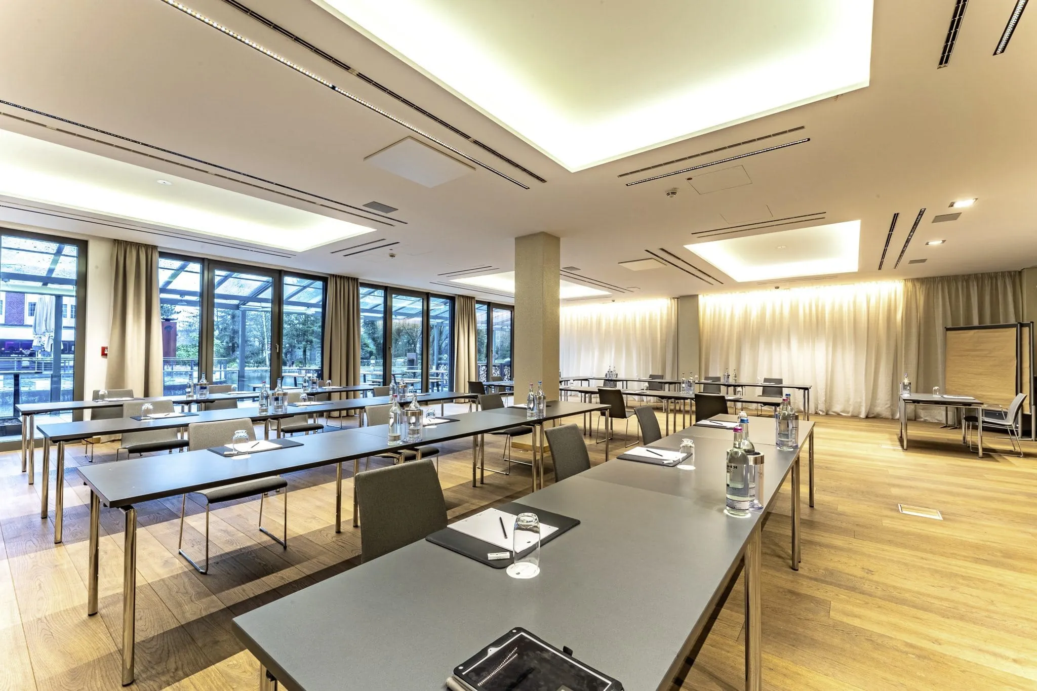 großer Tagungsraum mit schwarzen breiten Tischen im Wellings Parkhotel und Blick nach draußen
