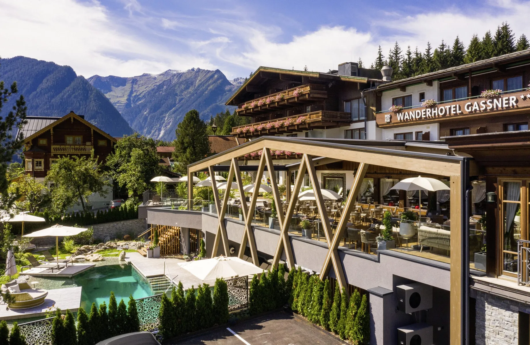 Wanderhotel Gassner in Neukirchen am Großvenediger mit Terrasse, Naturpool und Bergpanorama im Sommer