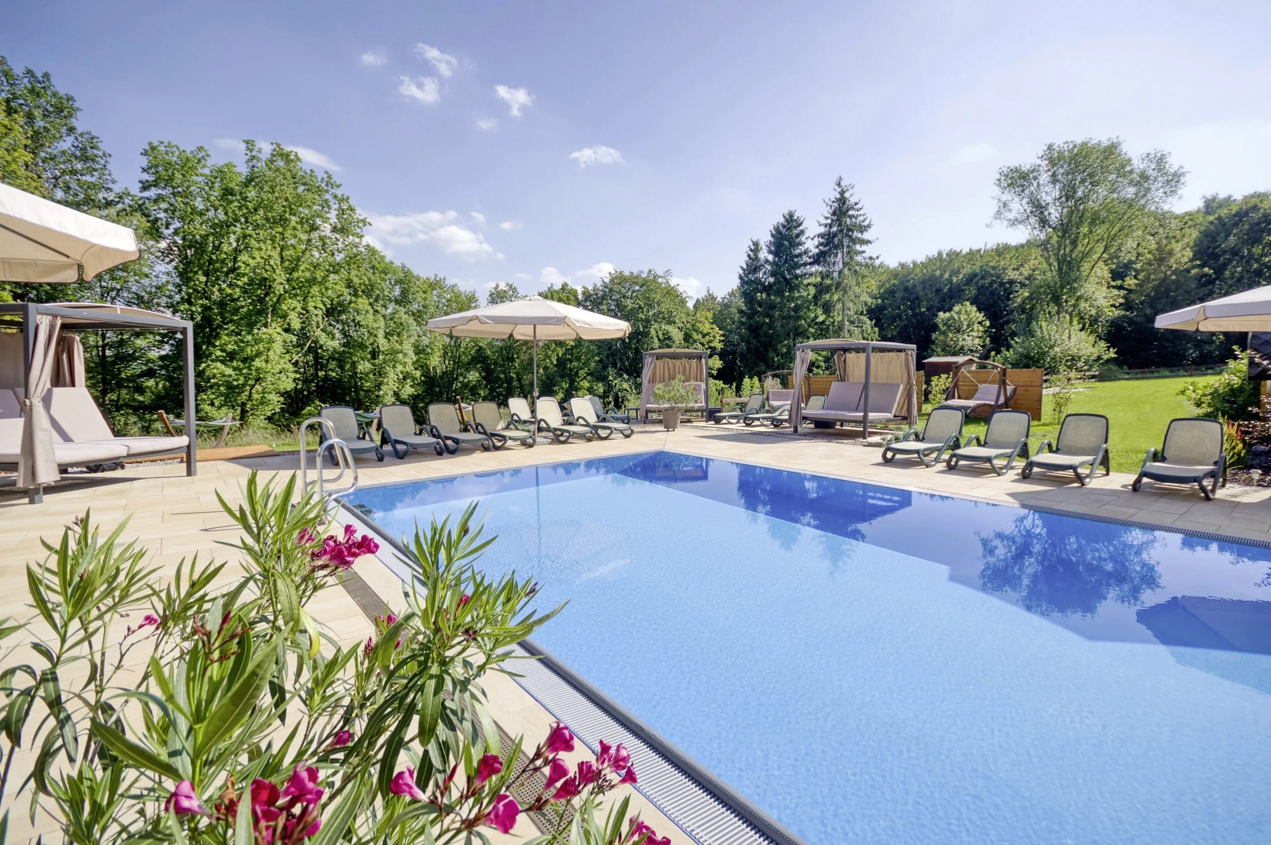 Outdoorpool mit umgebenden Liegen und Blick in die Natur im Wanderhotel in Th&uuml;ringen