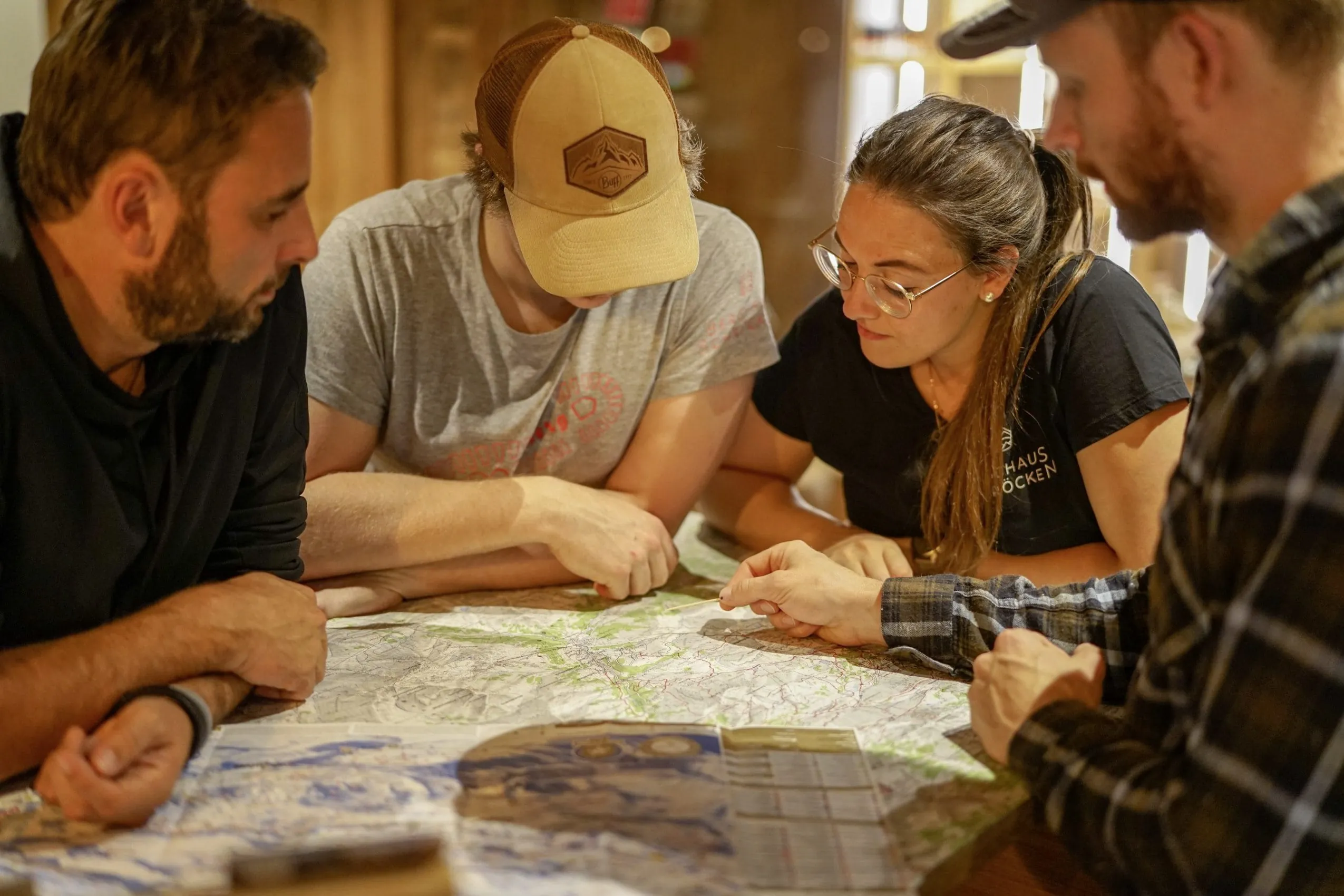 Gruppe plant Wanderroute am Tisch mit Wanderkarte im Berghaus Schr&ouml;cken
