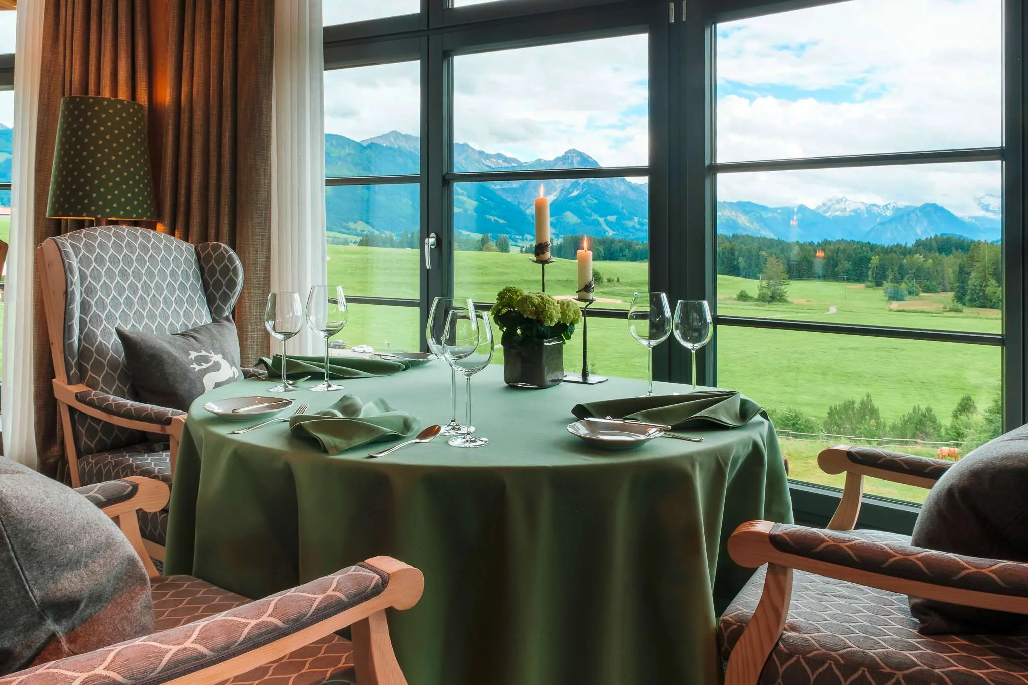 Gedeckter Tisch vor gro&szlig;em Panoramafenster im Restaurant Silberdistel im Sonnenalp Resort