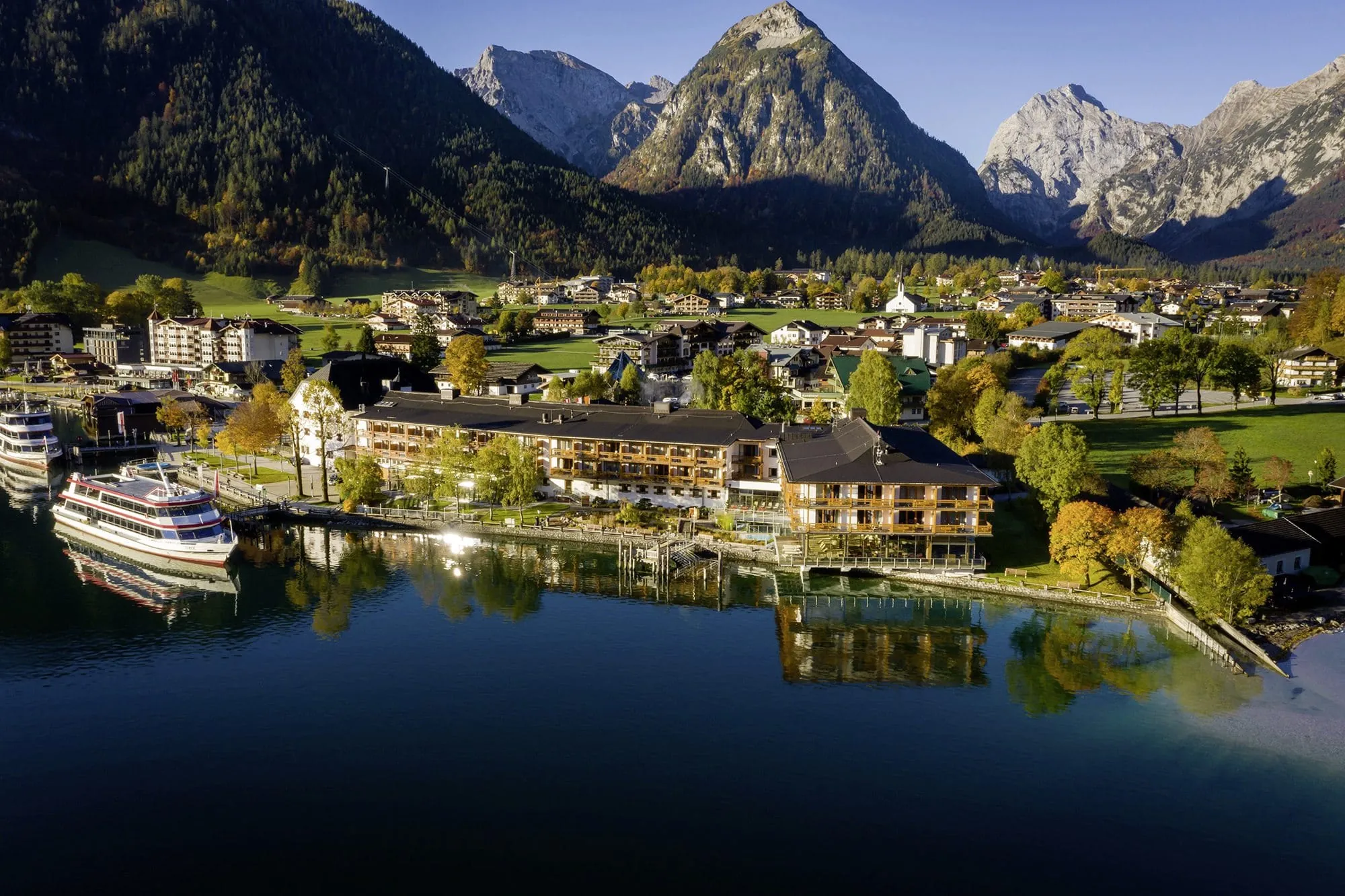 Luftaufnahme vom aja F&uuml;rstenhaus am Achensee mit Schiffsanlegestelle und Bergkulisse