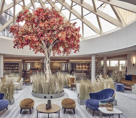 riesiger Baum unter der Kuppel in der Lobby mit Gräsern im Falkensteiner Kronplatz