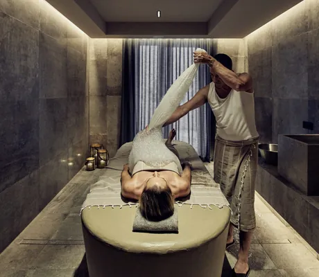 Frau liegt auf Hamam-Stein und Mann behandelt sie mit Schaum im Falkensteiner Kronplatz