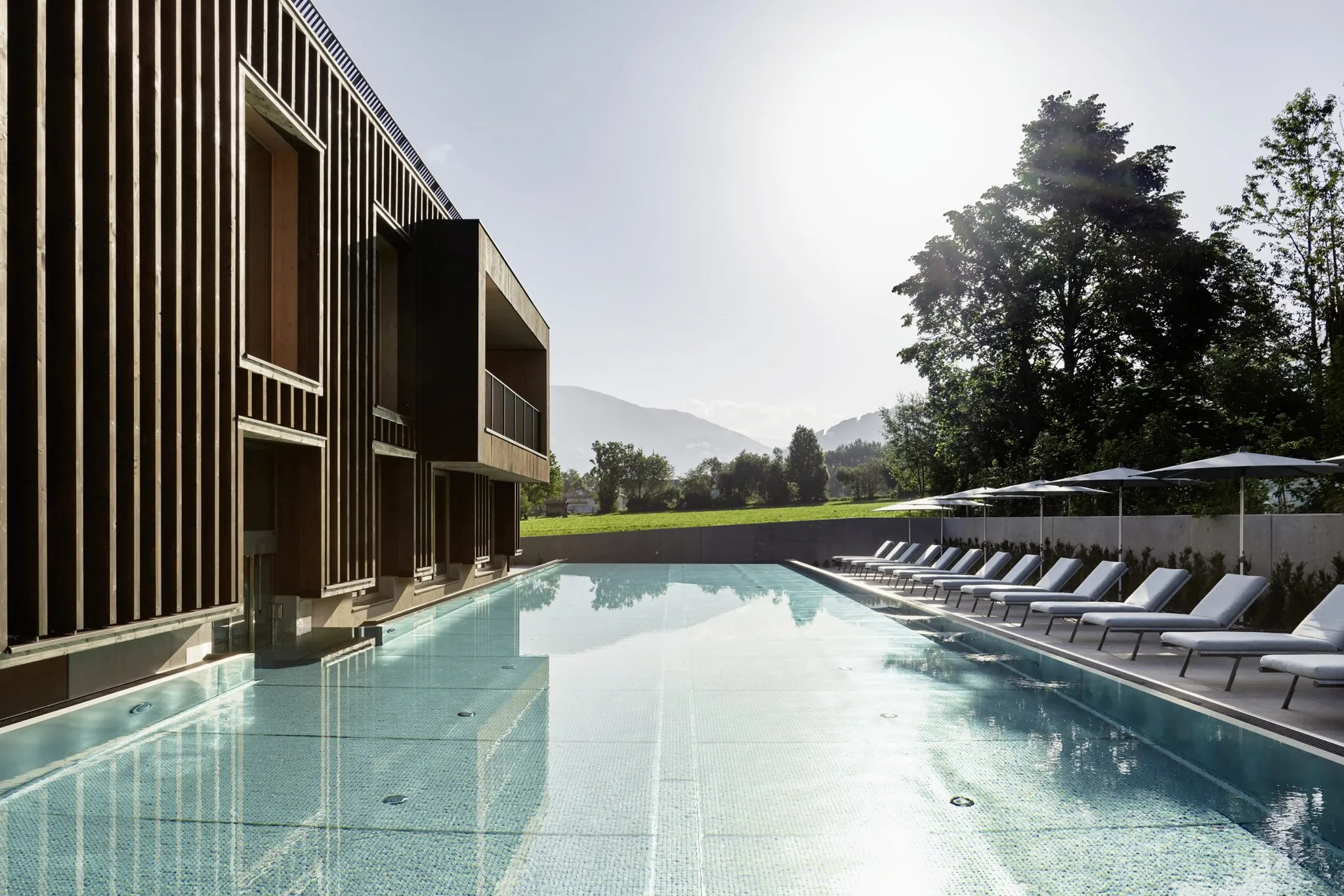 Sportpool im Falkensteiner Kronplatz mit Holzfassade und Sonnenliegen