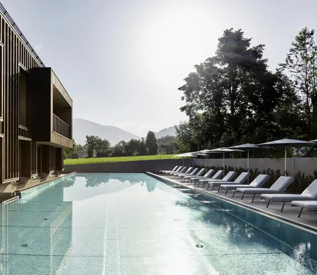 Sportpool im Falkensteiner Kronplatz mit Holzfassade und Sonnenliegen