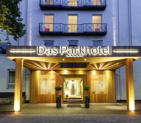 Eingang des Das Parkhotel mit beleuchtetem Schriftzug über der Tür