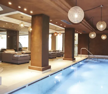 Indoorpool im Das Parkhotel mit kugelförmigen Leuchten über dem Wasser