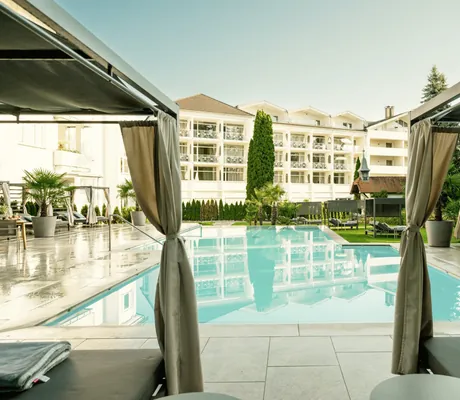 Blick von den Daybeds am Außenpool aus auf die Fassade des Das Parkhotel