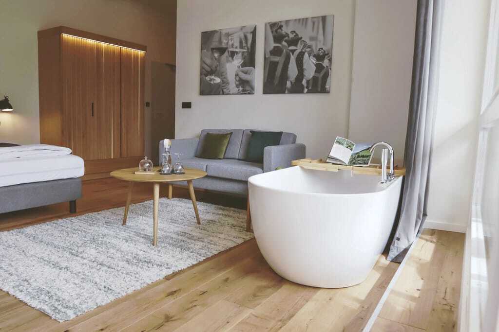 Zimmer im Das Parkhotel mit freistehender Badewanne und grauem Sofa