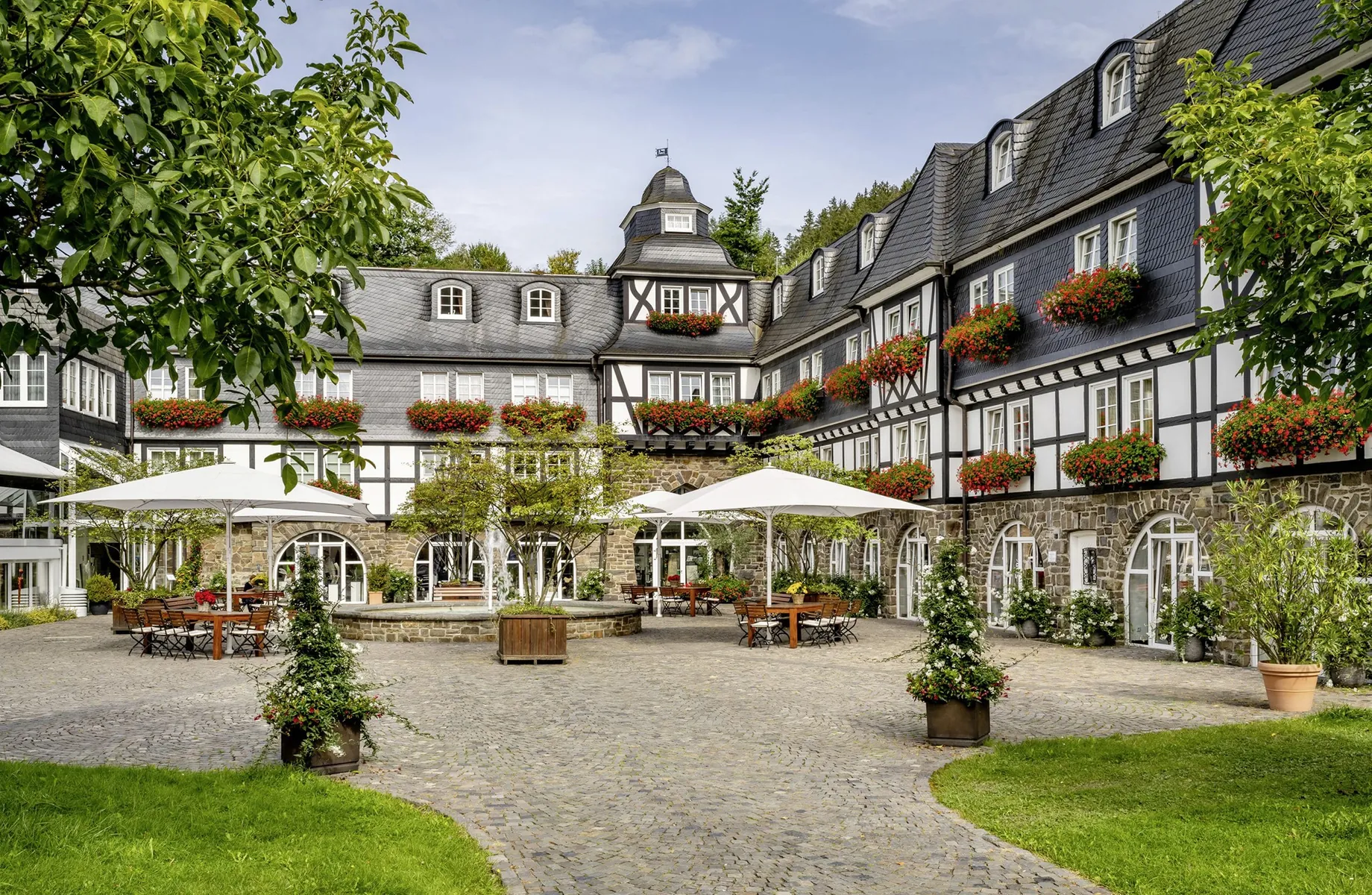Fachwerkfassade mit Innenhof und weißen Sonnenschirmen im Hotel Deimann