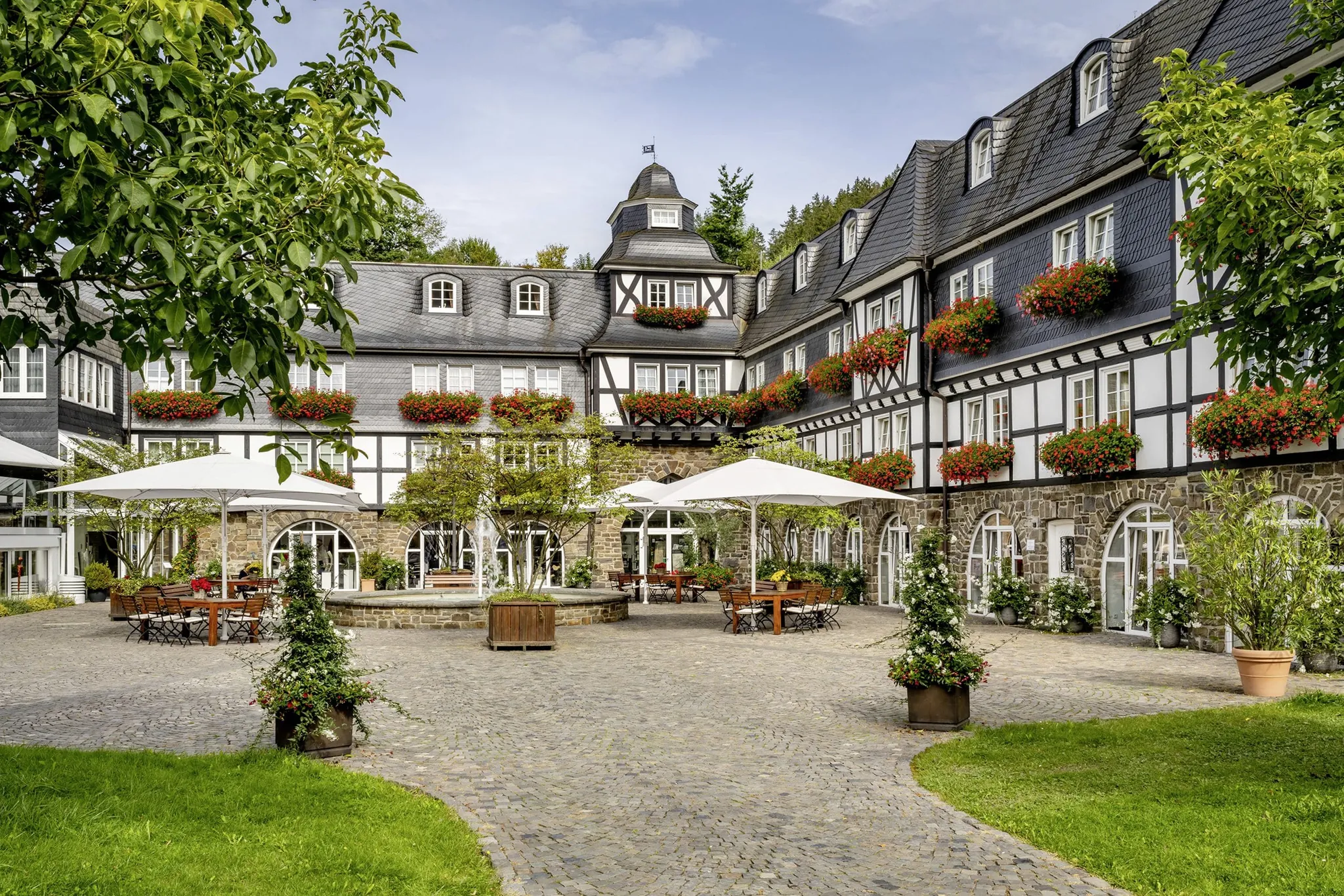 Fachwerkfassade mit Innenhof und weißen Sonnenschirmen im Hotel Deimann