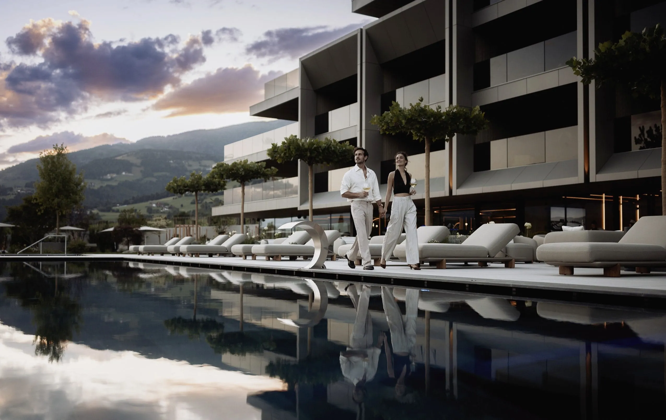 Paar in Abendkleidung läuft am Beckenrand des Outdoorpool des Hotel Solvie entlang