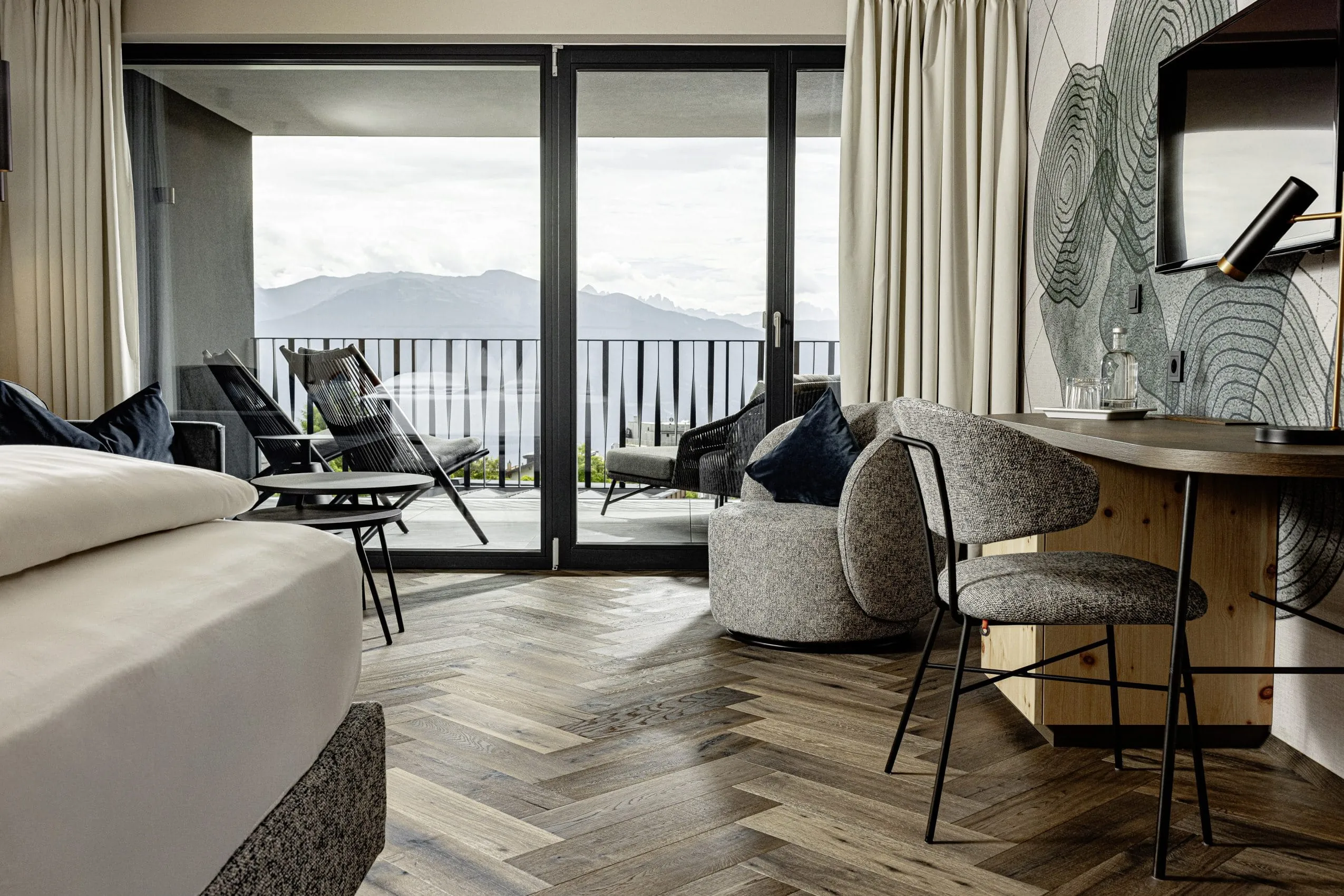 Zimmer im Sonnenberg Meransen mit Schreibtisch vor Wanddeko und Balkon mit Teakmöbeln