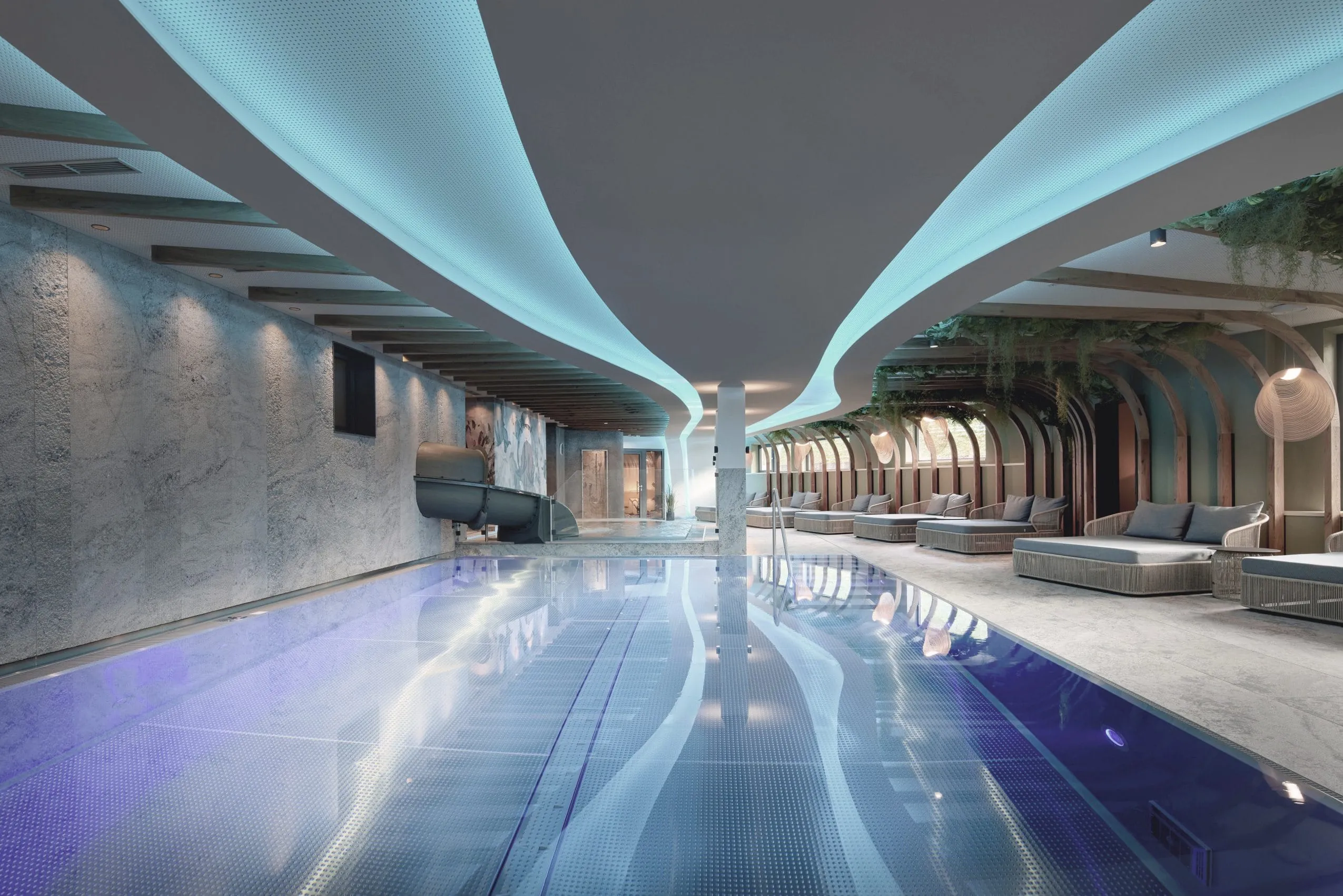 Indoorpool im Alpin SPA Hotel Tuxerhof mit wellenf&ouml;rmiger Deckenbeleuchtung und Wasserrutsche