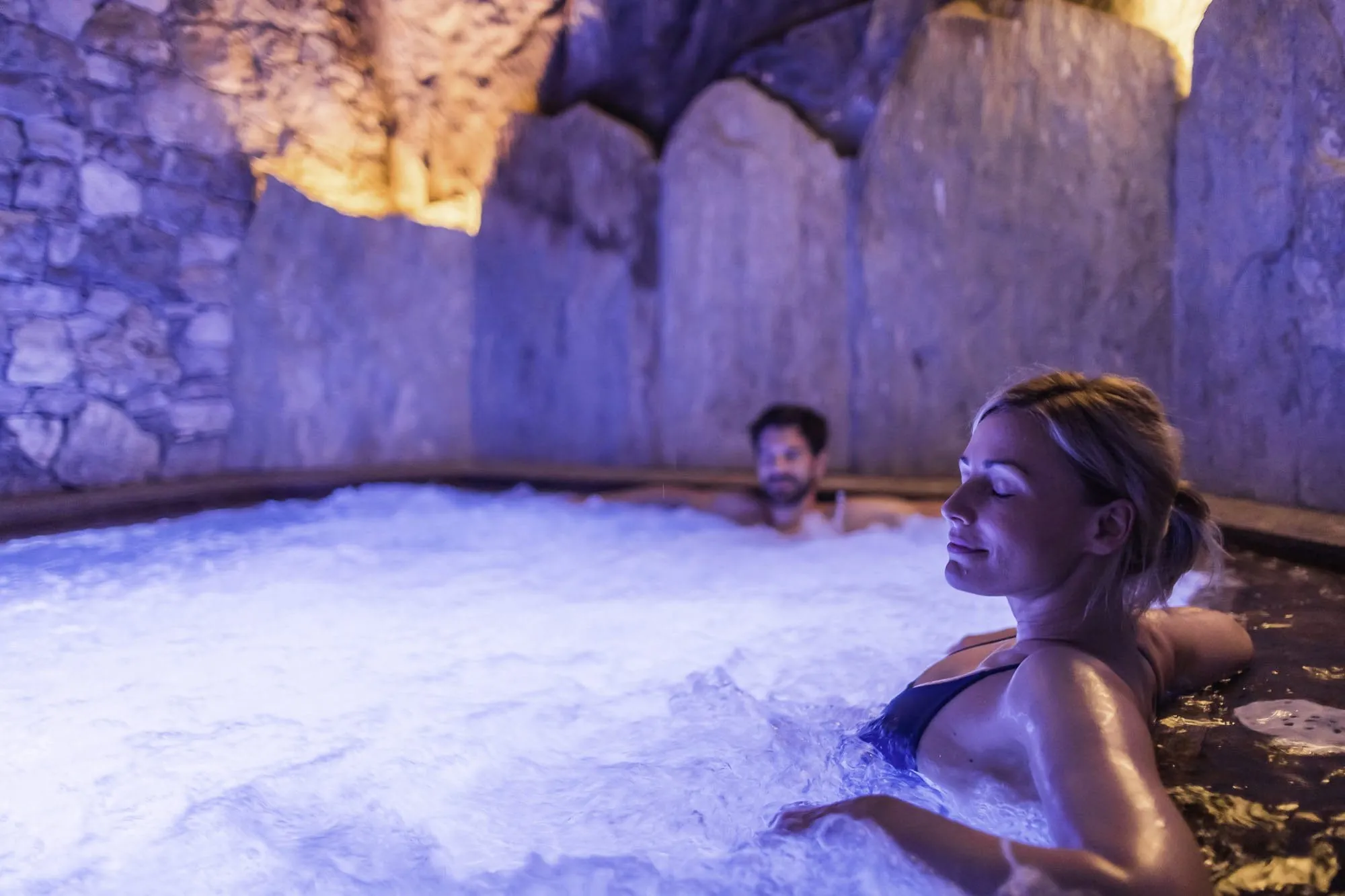 Paar sitzt im grottenartigen Whirlpool im Alpin SPA Hotel Tuxerhof und relaxt