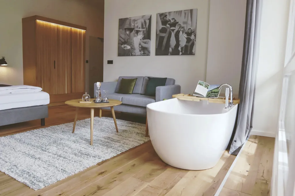 Zimmer im Das Parkhotel mit freistehender Badewanne und grauem Sofa