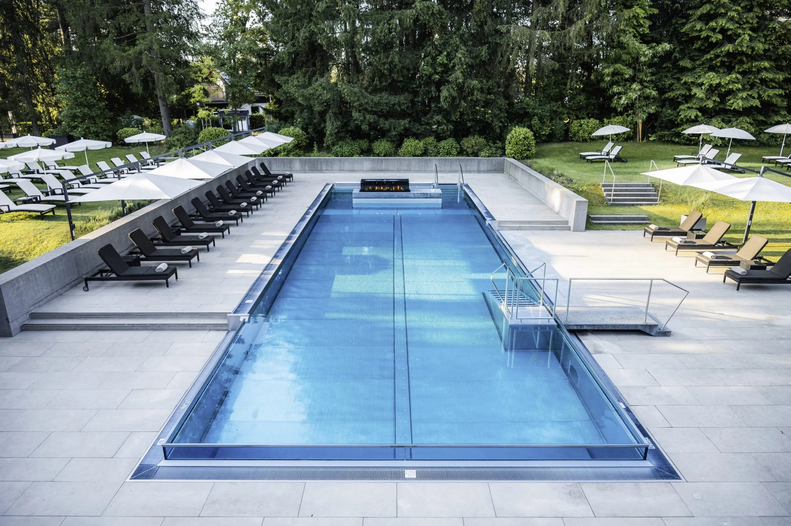 Blick aus der Luft auf den Outdoor-Infinitypool im Wellnesshotel Der Sonnenhof mit zahlreichen umgebenden Liegem&ouml;glichkeiten